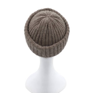 May include: A brown knitted beanie with a ribbed texture. The beanie is folded down at the brim, creating a cuff.