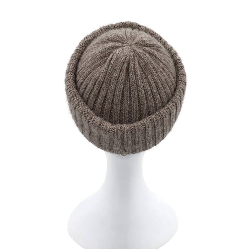 May include: A brown knitted beanie with a ribbed texture. The beanie is folded down at the brim, creating a cuff.