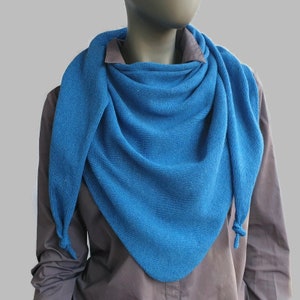 Könnte beinhalten: Ein blauer Strick-Schal mit dreieckiger Form und Quasten an den Enden. Der Schal ist um den Hals einer Schaufensterpuppe gelegt.