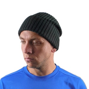 May include: A solid black knit beanie with a prominent vertical ribbed texture. The hat features a rounded crown and a snug fit, constructed from a thick, dark yarn material that covers the head down to the ears in a simple, functional design.