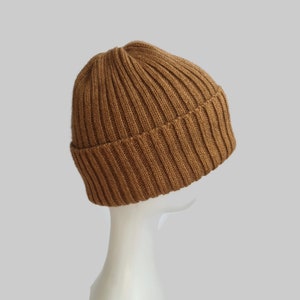 May include: A brown ribbed knit beanie hat. The hat is folded down at the brim and is made of a soft, warm material.