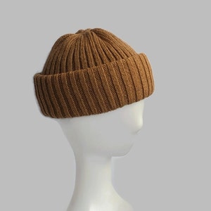 May include: A brown ribbed knit beanie hat. The hat is on a white mannequin head.