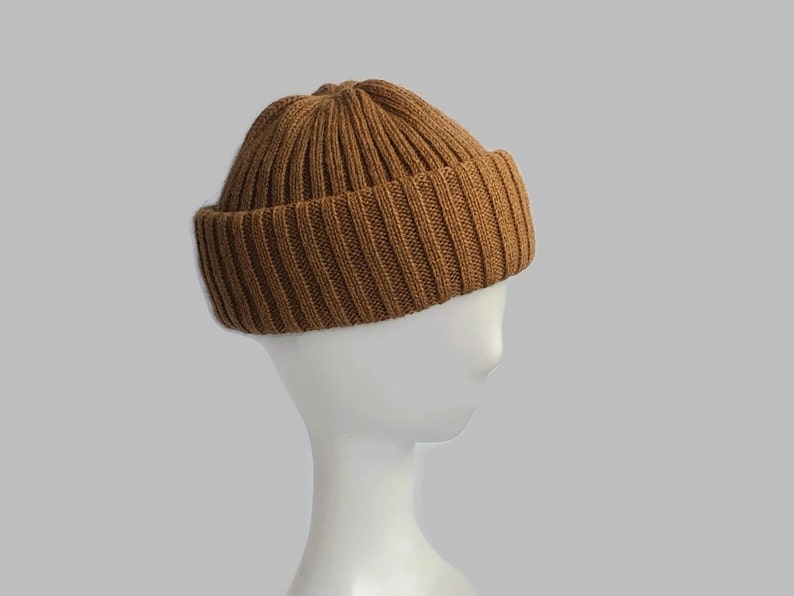 May include: A brown ribbed knit beanie hat. The hat is on a white mannequin head.