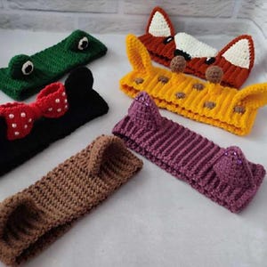 Peut inclure: Cinq bandeaux en crochet avec des oreilles d'animaux. Les bandeaux sont de différentes couleurs, notamment le marron, le vert, le noir, le jaune et le violet. Les oreilles sont faites pour ressembler à celles d'un renard, d'une grenouille, d'un ours, d'une souris et d'une girafe.