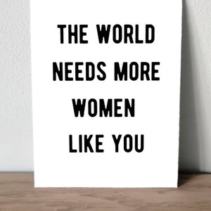 Op de afbeelding: Zwart-witte print met de tekst "De wereld heeft meer vrouwen nodig zoals jij".