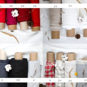 May include: A collection of fabric rolls in various colors and patterns, including red, white, gray, and black. The fabric rolls are arranged in rows on a white surface. The fabric rolls are labeled with numbers.