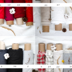 Pu&ograve; includere: Una collezione di rotoli di tessuto in vari colori e motivi, tra cui rosso, bianco, grigio e nero. I rotoli di tessuto sono disposti in file su una superficie bianca. I rotoli di tessuto sono etichettati con numeri.