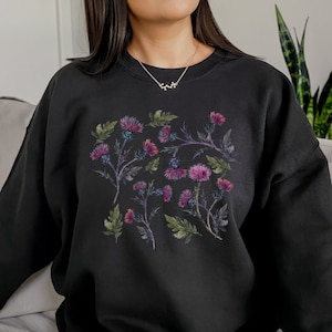 May include: Black sweatshirt with a floral print of purple and pink flowers on a black background.