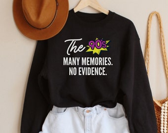 May include: Black sweatshirt with a white graphic that says "The 90s Many Memories. No Evidence." The graphic is a yellow and purple comic book style speech bubble. The sweatshirt is worn with a pair of light blue denim shorts and a brown woven bag with white beads.