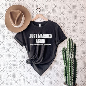 May include: A dark grey t-shirt with the text "Just Married Again This Time With The Right One" in white lettering.