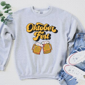 May include: A gray sweatshirt with the text "Oktober Fest" in a retro font and a graphic of two beer steins with foam on top.