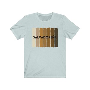 May include: Light blue t-shirt with a graphic of a horizontal stripe pattern in shades of brown and beige. The text "SALVADORE&Ntilde;A" is printed in black on the shirt.