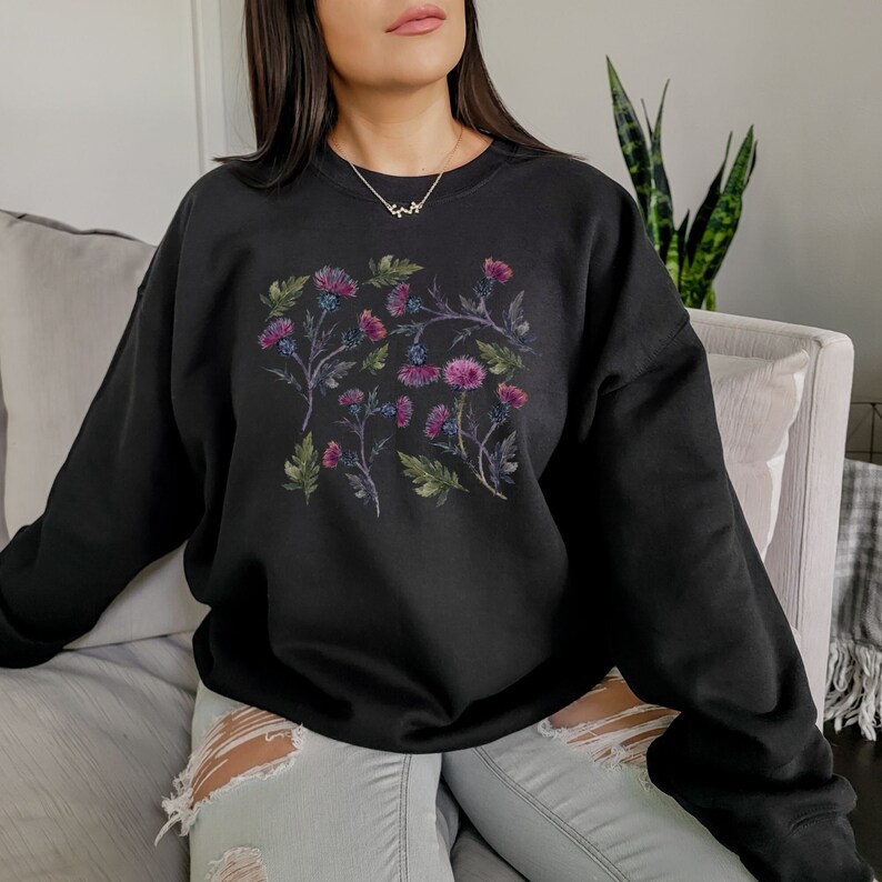 May include: Black sweatshirt with a floral print of purple and pink flowers on a black background.