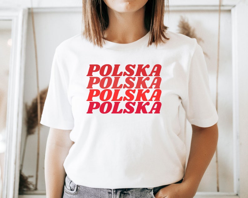 May include: White t-shirt with the word "POLSKA" repeated four times in red and pink lettering, stacked on top of each other.
