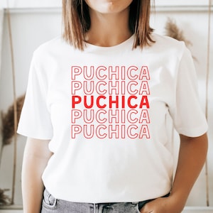 Puede incluir: Camiseta blanca con la palabra "Puchica" repetida cinco veces en texto rojo con contorno.