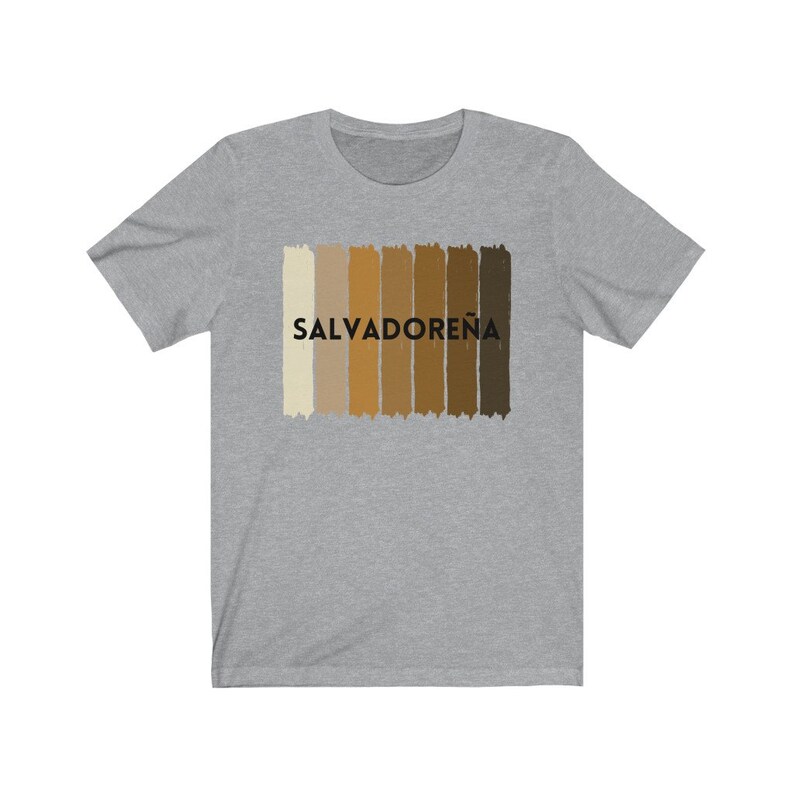 May include: A heather grey t-shirt with a graphic of a horizontal stripe pattern in shades of brown and beige. The text "SALVADORE&Ntilde;A" is printed in black on the shirt.
