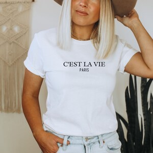 Pu&ograve; includere: Maglietta bianca con la scritta "C'est la vie Paris" stampata sul davanti.