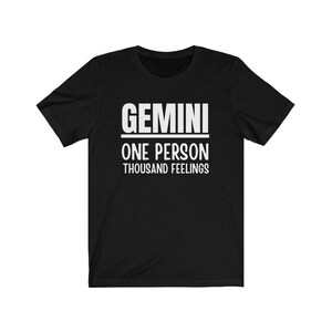 May include: Black t-shirt with white text that reads "GEMINI ONE PERSON THOUSAND FEELINGS".