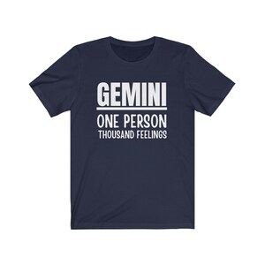May include: A navy blue t-shirt with white text that reads "GEMINI ONE PERSON THOUSAND FEELINGS".