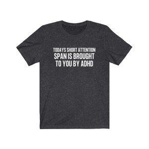 K&ouml;nnte beinhalten: Ein dunkelgraues T-Shirt mit dem Aufdruck "TODAYS SHORT ATTENTION SPAN IS BROUGHT TO YOU BY ADHD" in wei&szlig;.