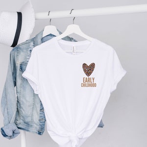 May include: White t-shirt with a brown leopard print heart and the text "EARLY CHILDHOOD" in brown.