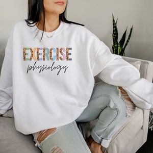 May include: White sweatshirt with the text "EXERCISE physiology" in colorful letters with a leopard print pattern.