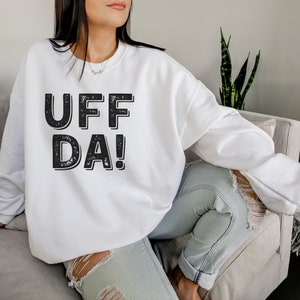 May include: White sweatshirt with a black distressed graphic that says "UFF DA!"