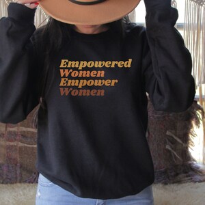 May include: Black sweatshirt with the text "Empowered Women Empower Women" in brown and orange lettering.