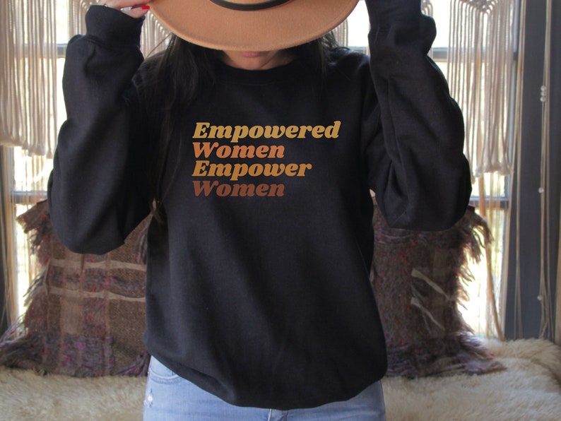 May include: Black sweatshirt with the text "Empowered Women Empower Women" in brown and orange lettering.