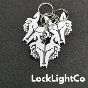 May include: A set of four white wolf head keychains with silver key rings. The keychains are stacked on top of each other. The text "LockLightCo" is printed in white on a black background.