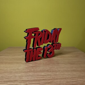 May include: A 3D printed red and black sign that reads "Friday the 13th".