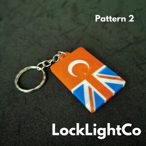 May include: Orange and blue keychain with a crescent moon and a Union Jack pattern. The keychain is labeled "LockLightCo" and "Pattern 2".