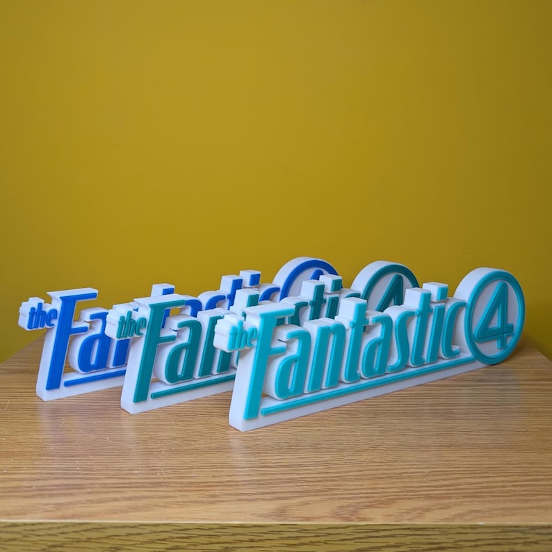 May include: Three white and blue "Fantastic Four" logo signs. The signs have a 3D effect with the words "the Fantastic 4" in blue and teal. The background is a solid yellow color.