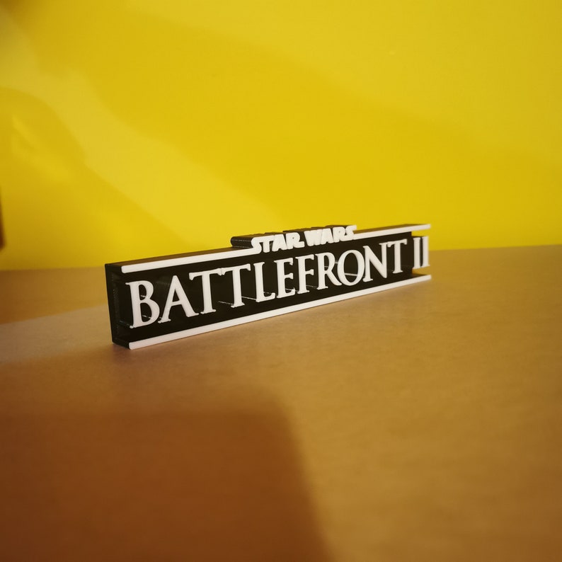 May include: A black and white 3D printed sign with the text "STAR WARS BATTLEFRONT II" in white letters.