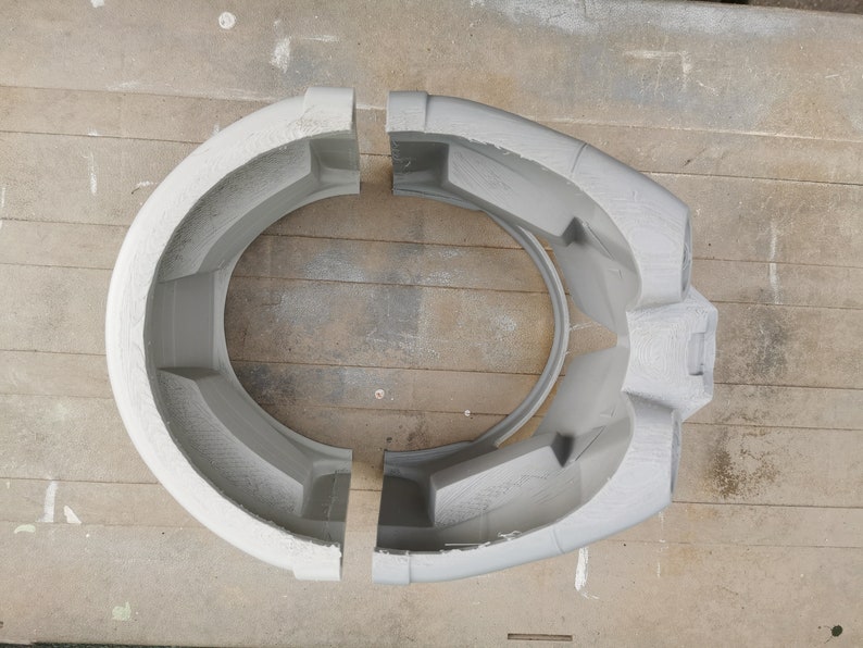 May include: Two gray plastic pieces that fit together to form a helmet. The pieces are separated and show the inside of the helmet.