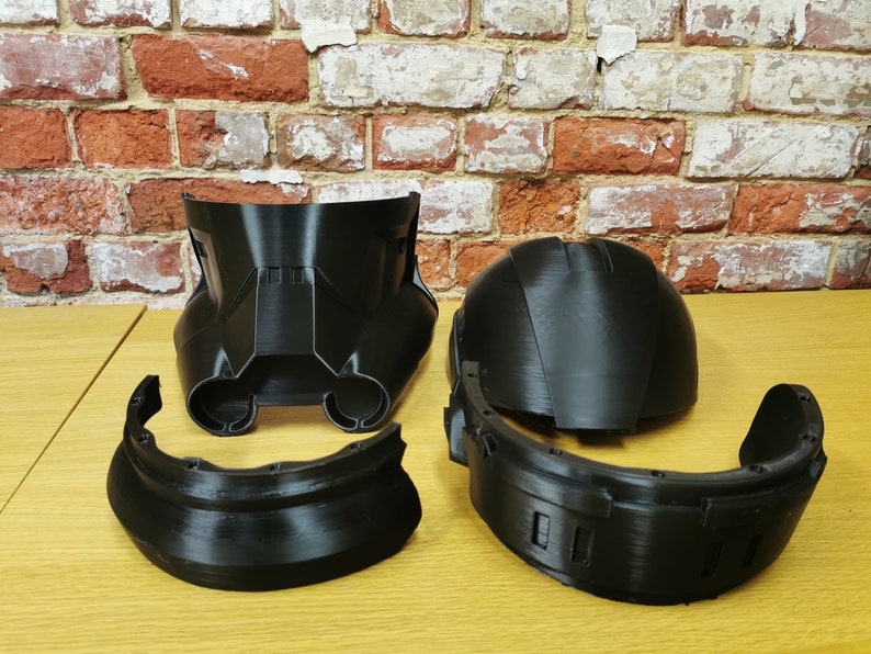 Puede incluir: Un casco de pl&aacute;stico negro desmontado en cinco piezas. El casco est&aacute; formado por una c&uacute;pula, una pieza frontal y tres piezas m&aacute;s peque&ntilde;as que se conectan a la c&uacute;pula y a la pieza frontal.