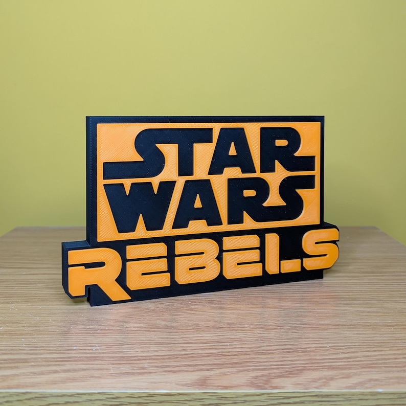 May include: A black and orange 3D printed sign with the text "Star Wars Rebels".