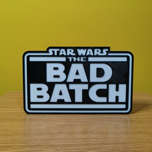 May include: A black and white sign with the text "STAR WARS THE BAD BATCH" in white letters on a black background.