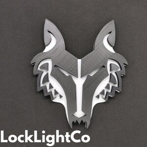 May include: Black and white wolf head silhouette wall decor. The wolf head is made of a layered, geometric design.