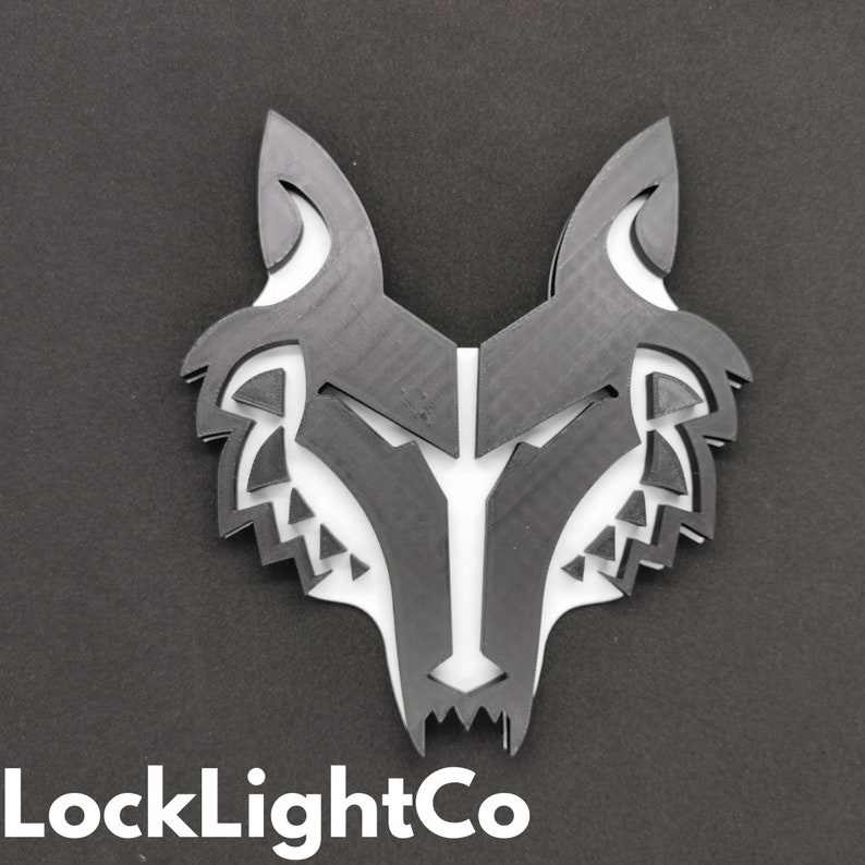 May include: Black and white wolf head silhouette wall decor. The wolf head is made of a layered, geometric design.