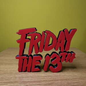 May include: Red and black 3D printed sign that reads "Friday the 13th".
