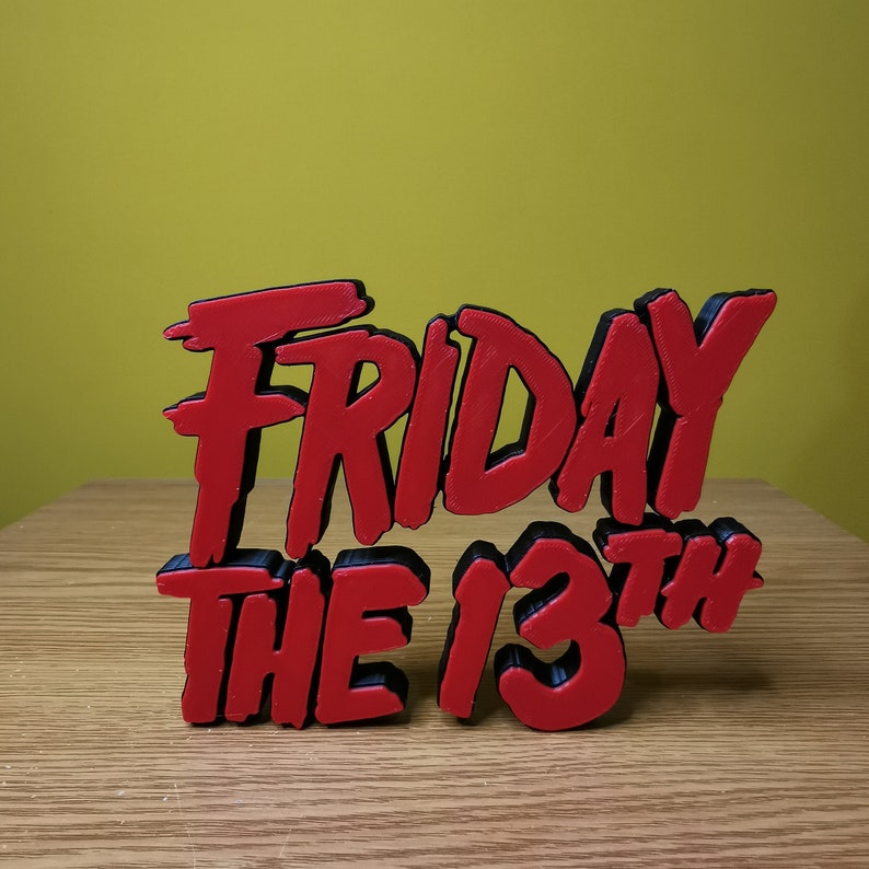 May include: Red and black 3D printed sign that reads "Friday the 13th".