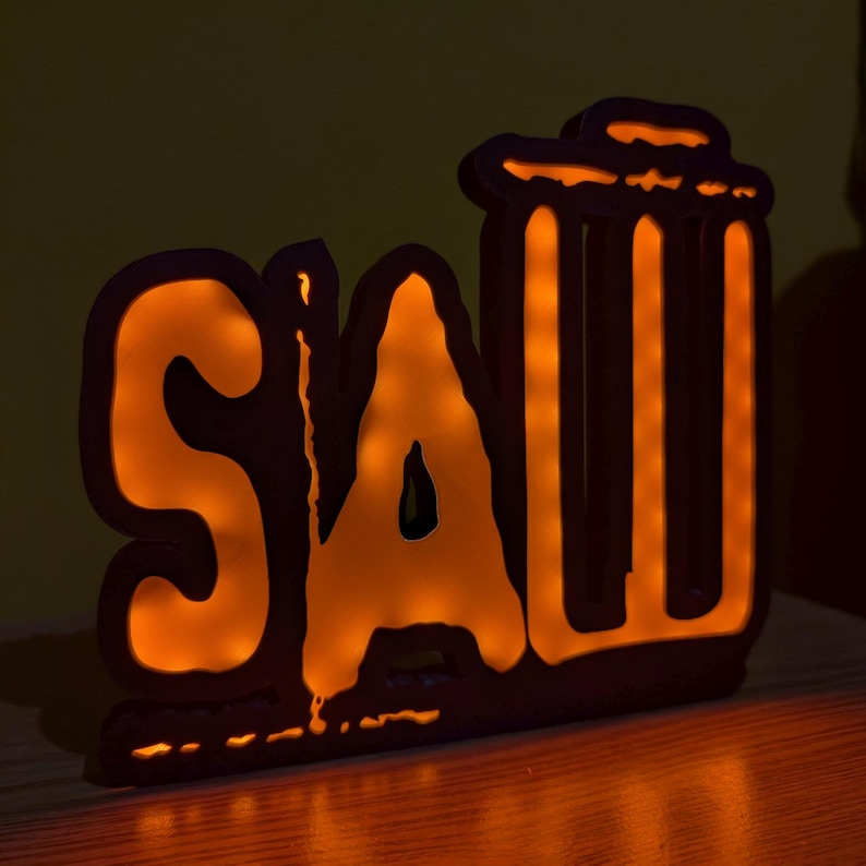 May include: A wooden sign with the word "SAW" in orange letters, with a stylized image of a trash can behind the word. The sign is lit from behind, creating a warm glow.