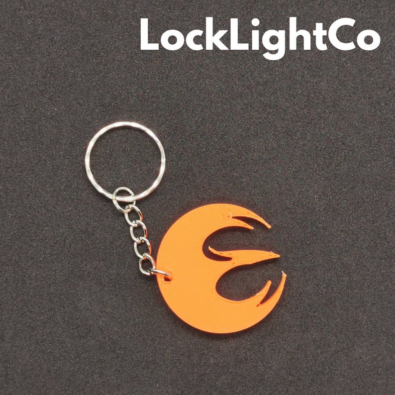 May include: Orange plastic keychain with a stylized flame design. The keychain is attached to a silver metal ring and chain.
