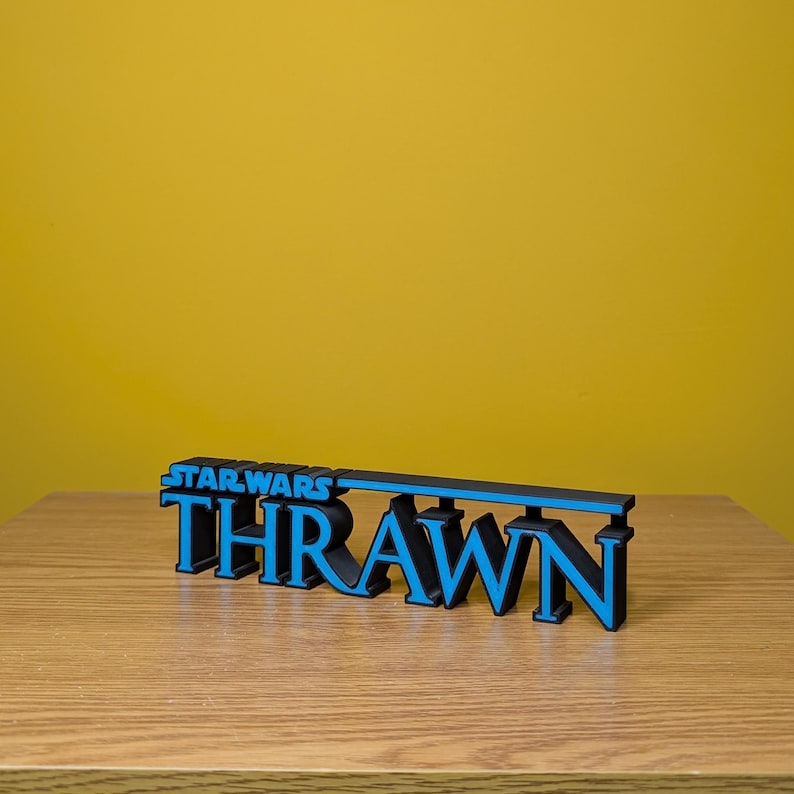 May include: A black and blue 3D printed sign that reads "STAR WARS THRAWN".