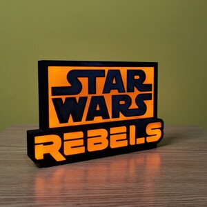 May include: Black and orange light-up sign with the text "Star Wars Rebels".