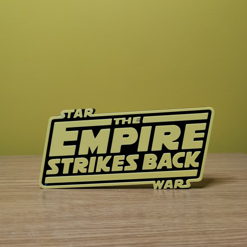 May include: A yellow and black sign with the text "STAR WARS THE EMPIRE STRIKES BACK" in a bold, black font.