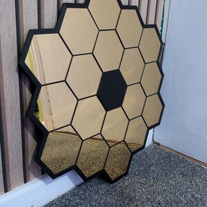 May include: A gold hexagonal mirror with black frames, arranged in a honeycomb pattern.