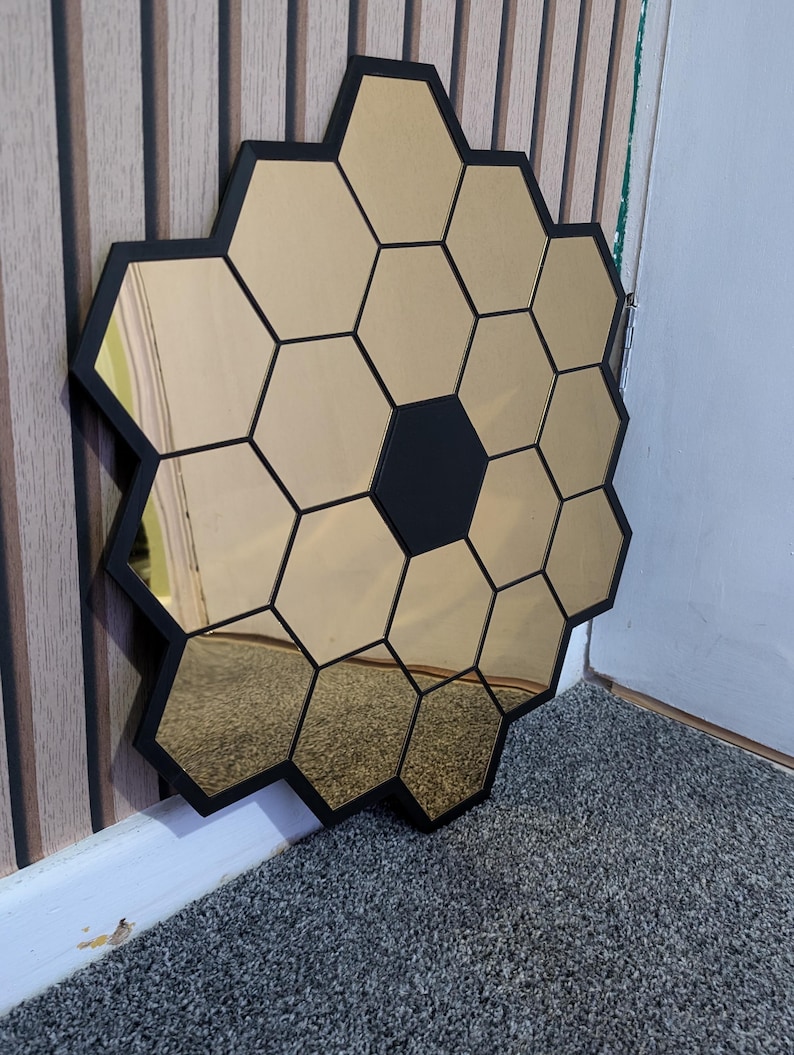 May include: A gold hexagonal mirror with black frames, arranged in a honeycomb pattern.