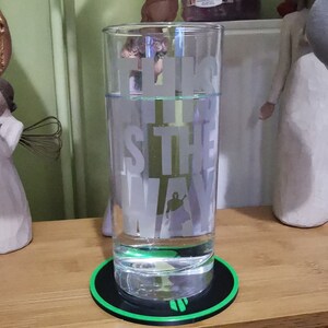 Puede incluir: Un vaso de vidrio transparente con el texto "This is the way" grabado en el lateral. El vaso est&aacute; lleno de agua y se encuentra sobre un posavasos redondo negro y verde.